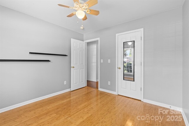 unfurnished room with ceiling fan, baseboards, and light wood-type flooring