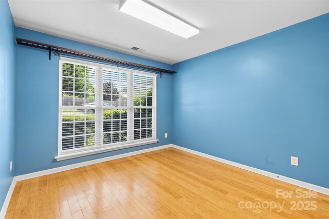 empty room with baseboards, wood finished floors, and visible vents