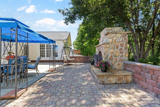 view of patio / terrace with outdoor dining space and an outdoor stone fireplace