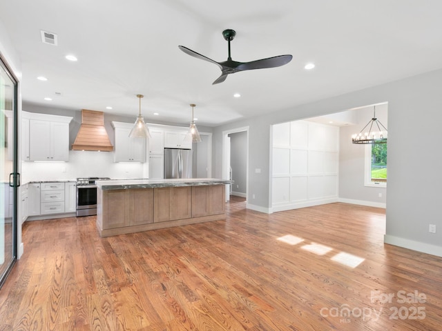 kitchen featuring appliances with stainless steel finishes, light wood-style floors, a kitchen island, visible vents, and custom exhaust hood
