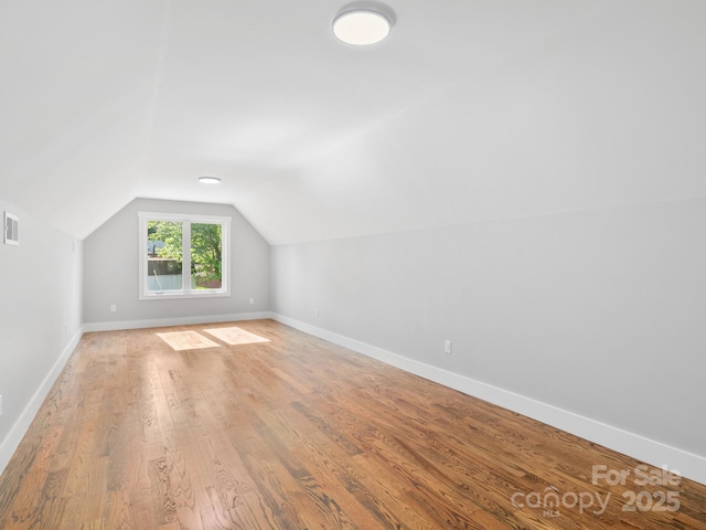 bonus room featuring baseboards, lofted ceiling, light wood-style flooring, and visible vents