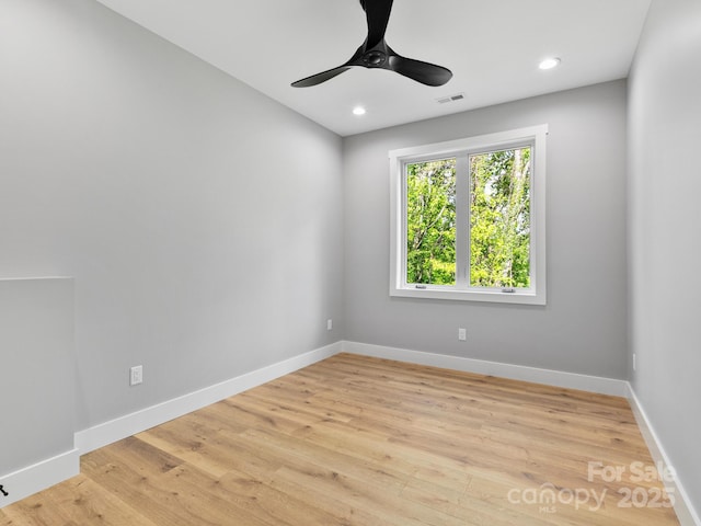 spare room with light wood finished floors, baseboards, a ceiling fan, and visible vents