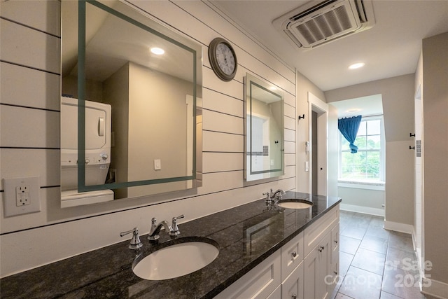 full bath featuring stacked washer and clothes dryer, baseboards, tile patterned flooring, double vanity, and recessed lighting