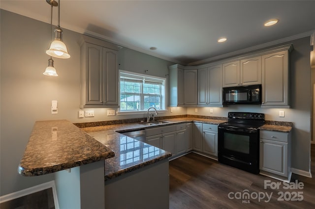 kitchen with black appliances, a peninsula, a sink, ornamental molding, and dark wood-style flooring