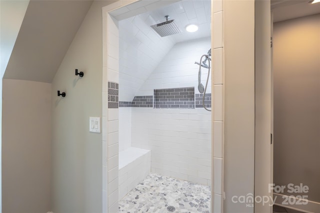 full bathroom with a tile shower and lofted ceiling
