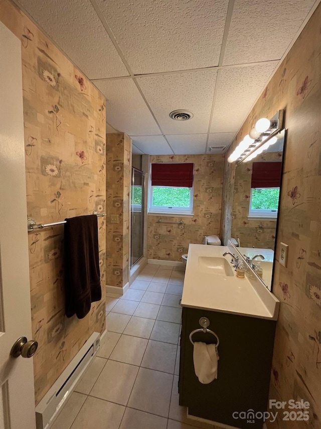 bathroom with a paneled ceiling, a stall shower, vanity, tile patterned floors, and a baseboard heating unit