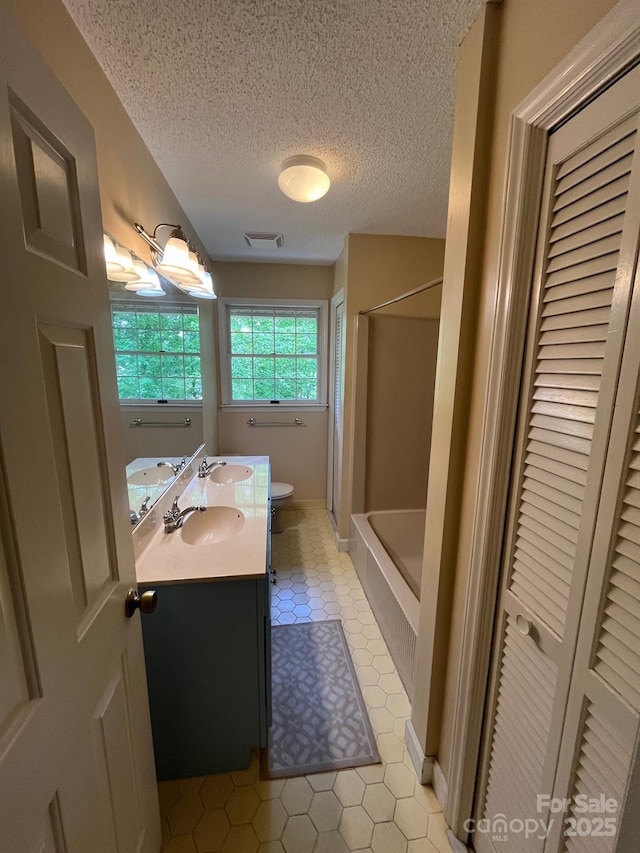 bathroom with double vanity, a textured ceiling, visible vents, a closet, and toilet