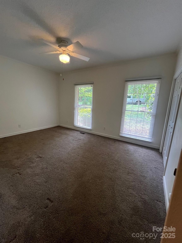 carpeted empty room featuring baseboards, a textured ceiling, and ceiling fan
