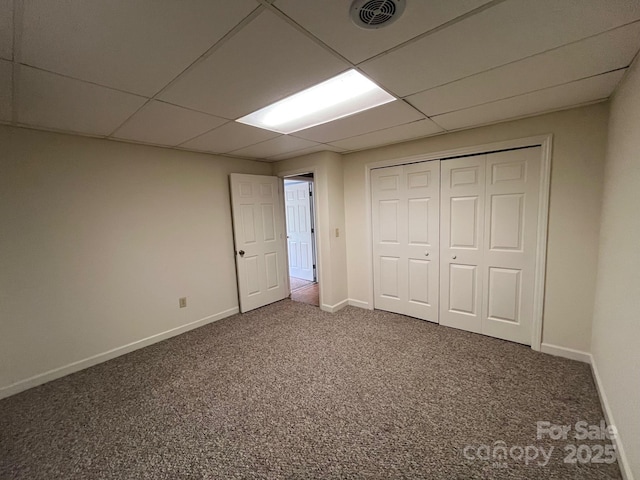 unfurnished bedroom with baseboards, visible vents, a paneled ceiling, and carpet