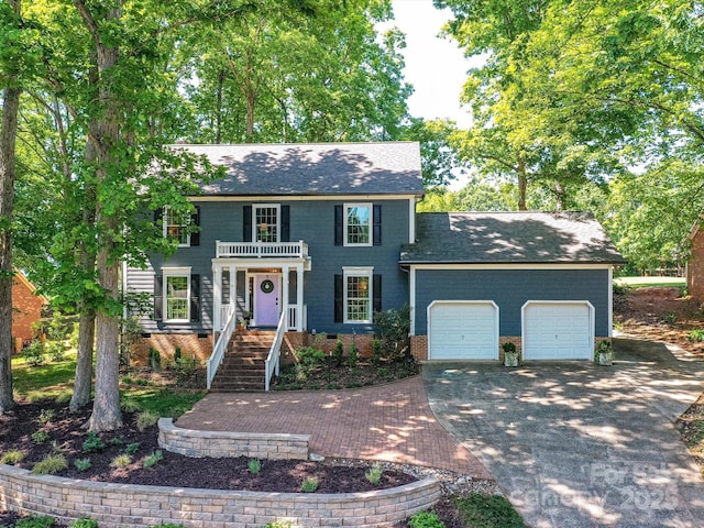colonial-style house featuring a balcony, a shingled roof, crawl space, concrete driveway, and an attached garage