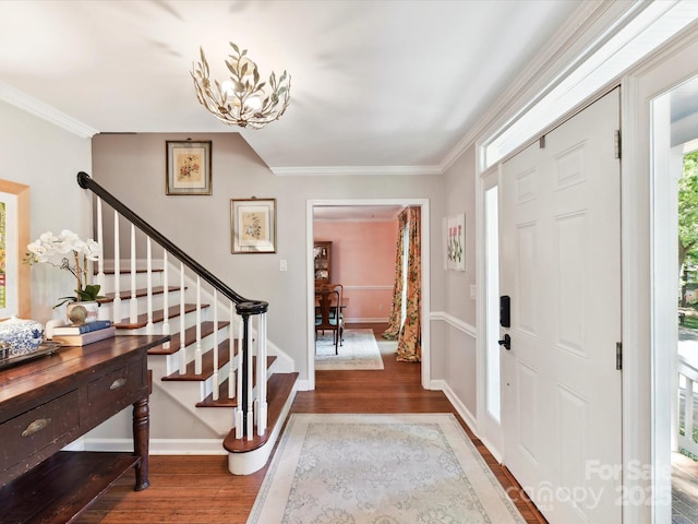 entryway with crown molding, a notable chandelier, wood finished floors, and stairway