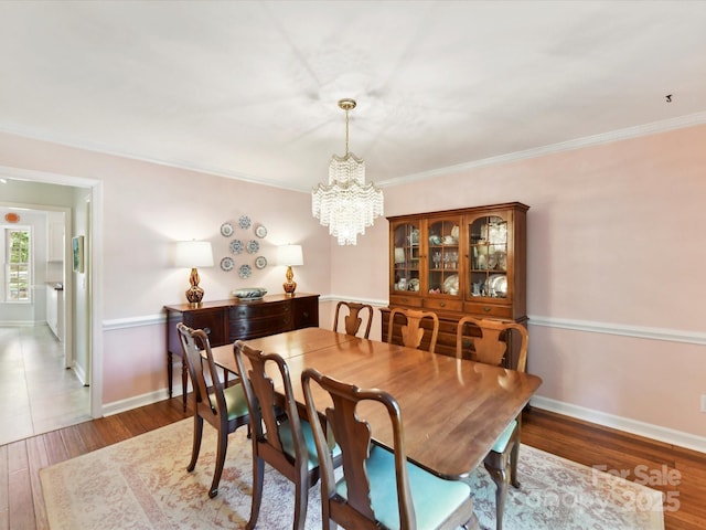dining space featuring crown molding, baseboards, wood finished floors, and a chandelier