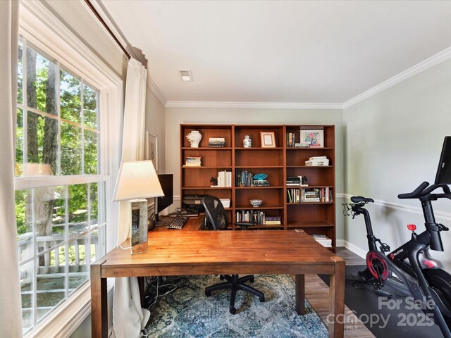 home office with crown molding, wood finished floors, a healthy amount of sunlight, and visible vents