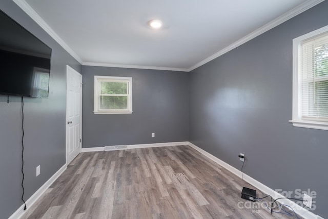 spare room featuring baseboards, visible vents, a healthy amount of sunlight, and wood finished floors