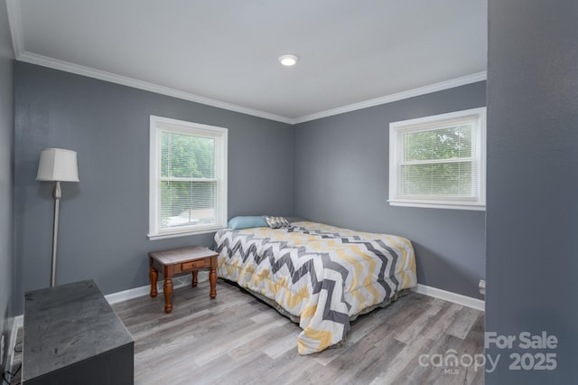 bedroom with baseboards, ornamental molding, and wood finished floors