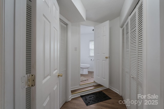 bathroom featuring a closet, wood finished floors, toilet, baseboards, and a textured ceiling