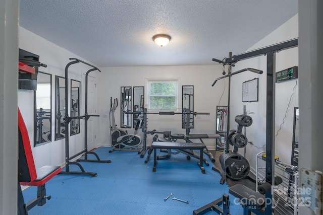 exercise room with baseboards and a textured ceiling