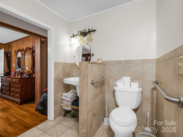 bathroom with crown molding, toilet, tile walls, a wainscoted wall, and tile patterned floors