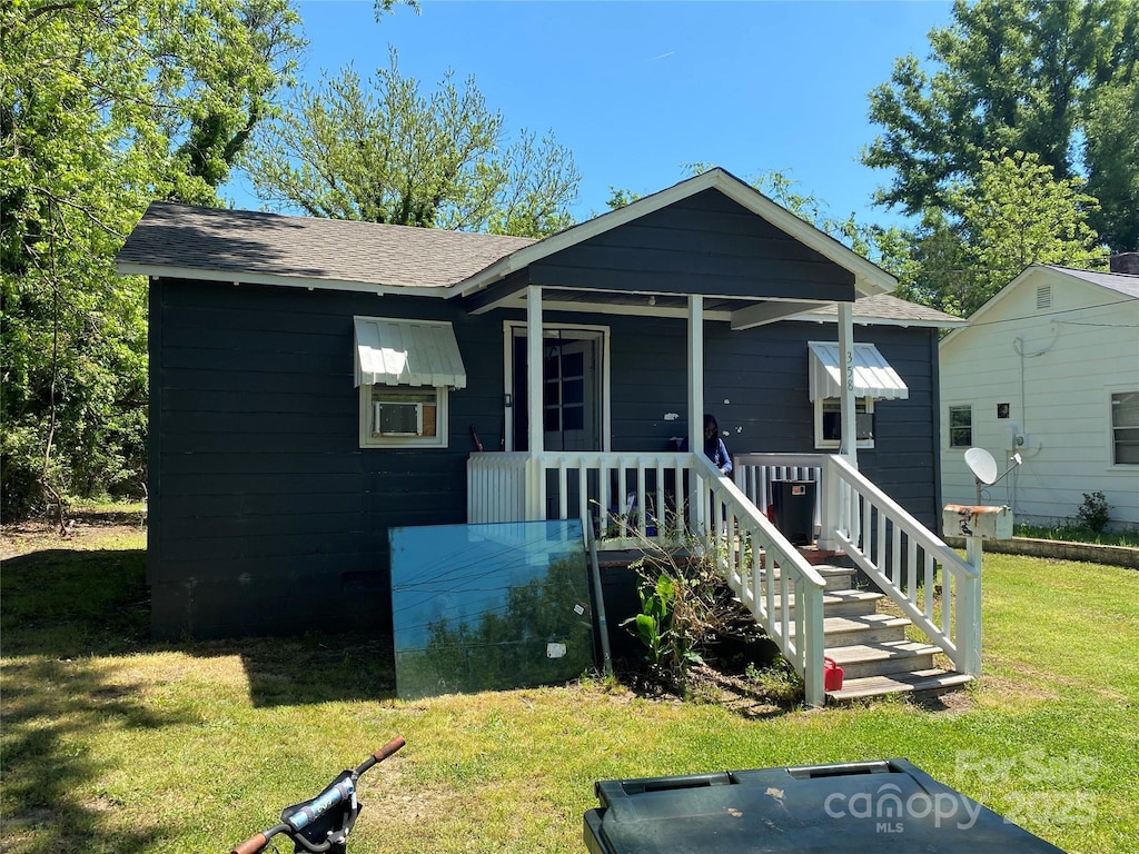 bungalow-style home with a porch, a shingled roof, and a front lawn