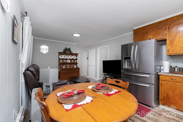 dining space with crown molding and light wood-style flooring