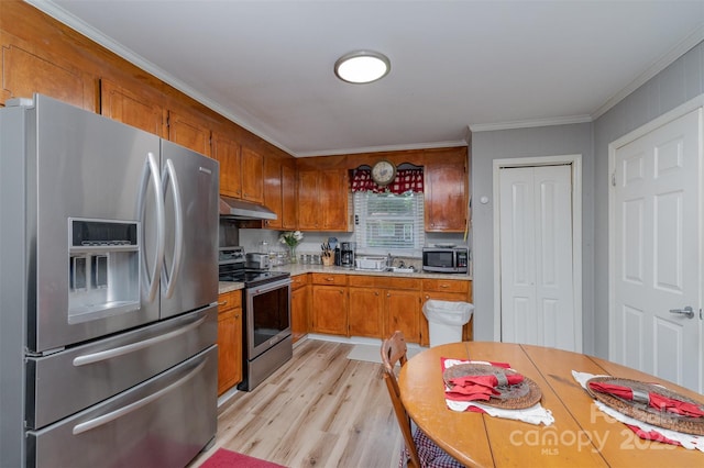 kitchen featuring brown cabinets, appliances with stainless steel finishes, light wood finished floors, light countertops, and under cabinet range hood