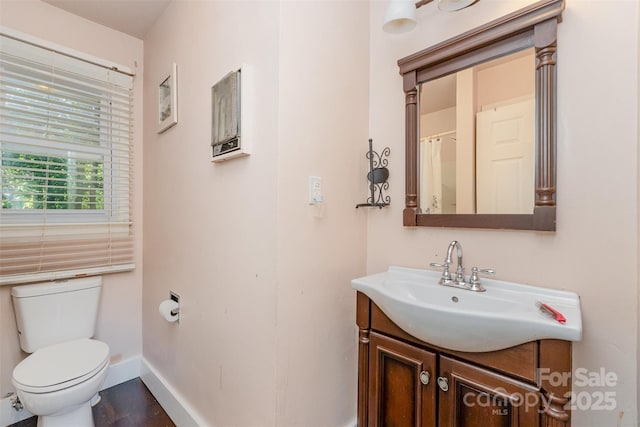 bathroom with baseboards, toilet, and vanity