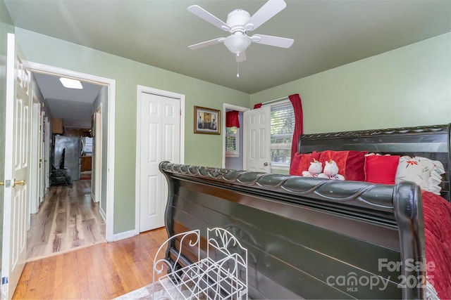 bedroom with baseboards, ceiling fan, a closet, and light wood finished floors