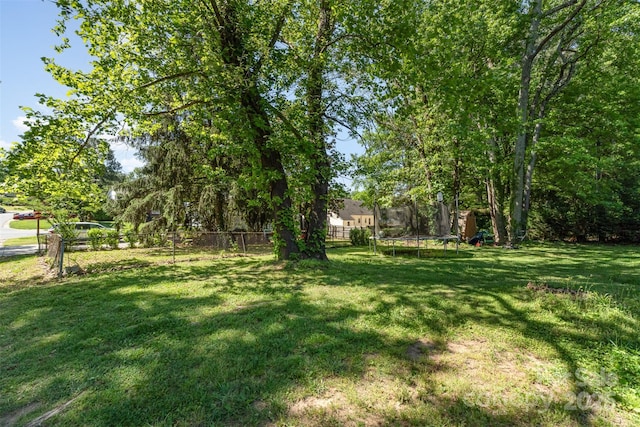 view of yard with a trampoline and fence