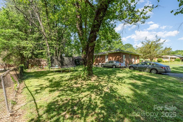 view of yard with fence and a trampoline