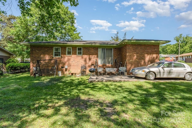 back of house featuring a yard, a patio area, and brick siding