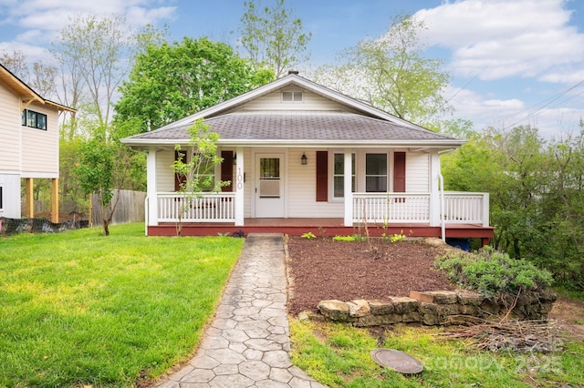 bungalow-style house with covered porch, a shingled roof, and a front yard