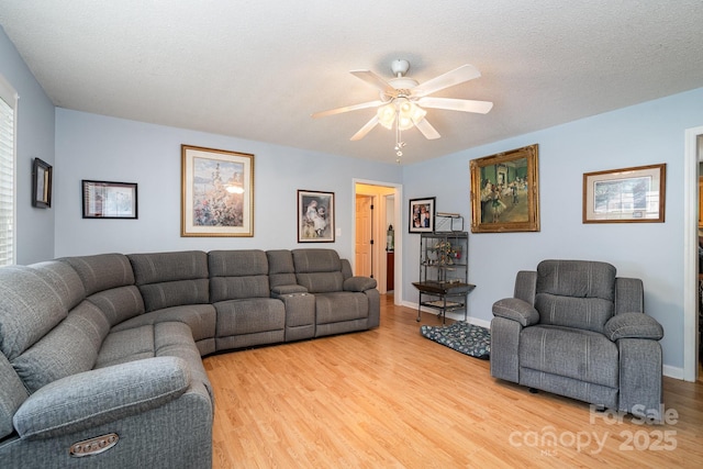 living area with baseboards, a ceiling fan, and light wood finished floors