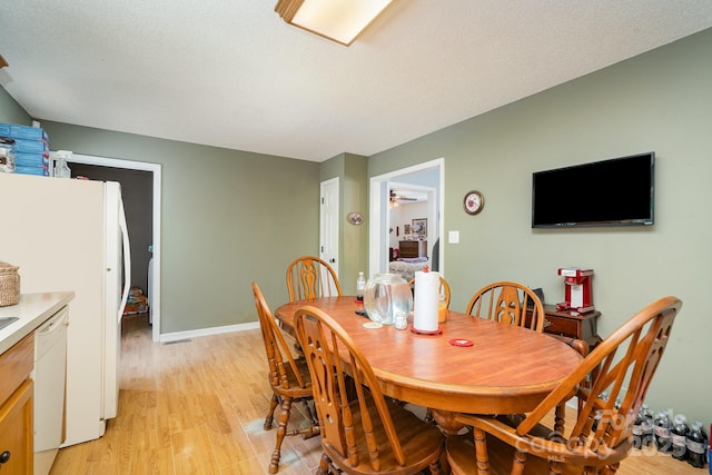dining area with baseboards, a textured ceiling, light wood finished floors, and ceiling fan