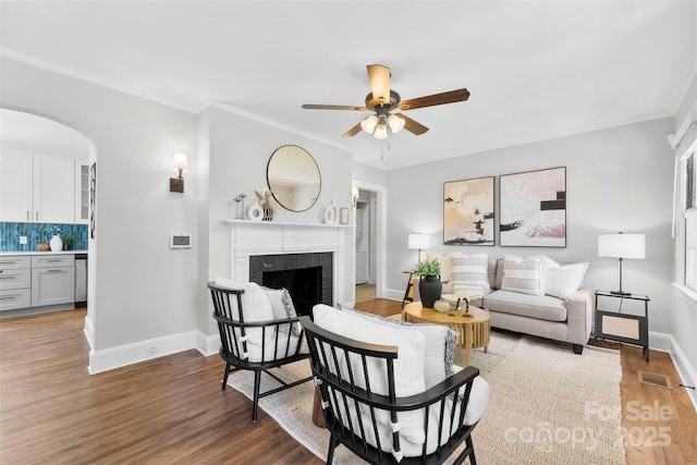 living area with visible vents, a ceiling fan, a fireplace, baseboards, and arched walkways