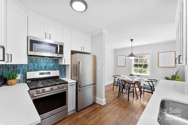 kitchen with decorative backsplash, appliances with stainless steel finishes, dark wood finished floors, white cabinets, and ornamental molding