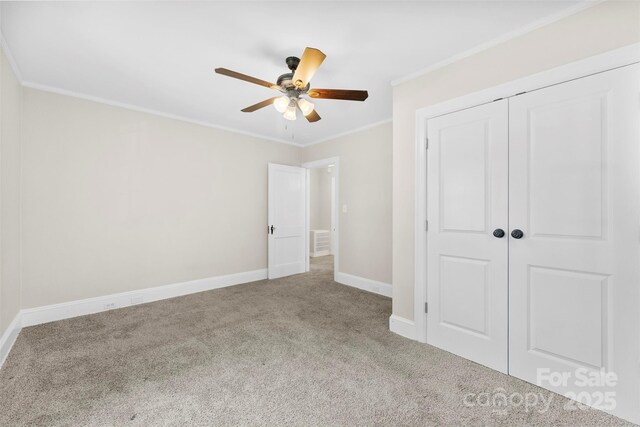 unfurnished bedroom with ceiling fan, carpet, baseboards, ornamental molding, and a closet