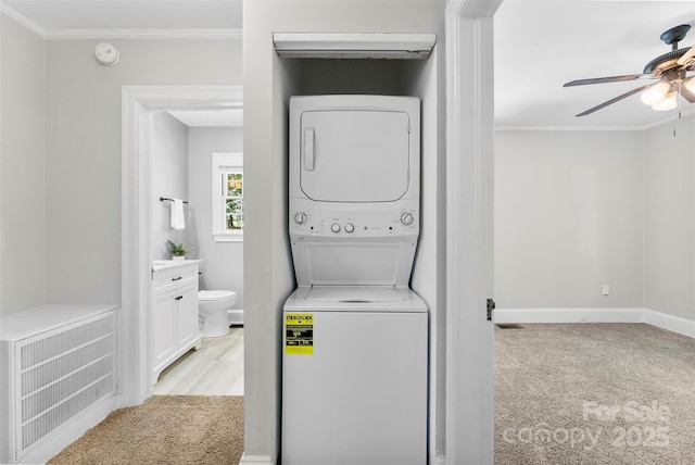clothes washing area featuring ceiling fan, laundry area, stacked washer / drying machine, baseboards, and ornamental molding
