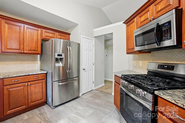 2379 Whitley Rd, Fort Mill, SC 29708 - kitchen featuring appliances with stainless steel finishes, vaulted ceiling, light stone counters, brown cabinetry, and decorative backsplash