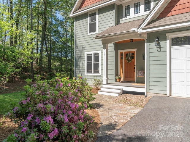 view of exterior entry with roof with shingles