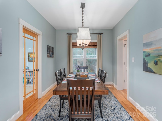 dining space with an inviting chandelier, light wood-style floors, and baseboards