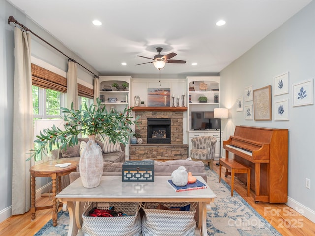 living area featuring a fireplace, a ceiling fan, baseboards, recessed lighting, and wood finished floors