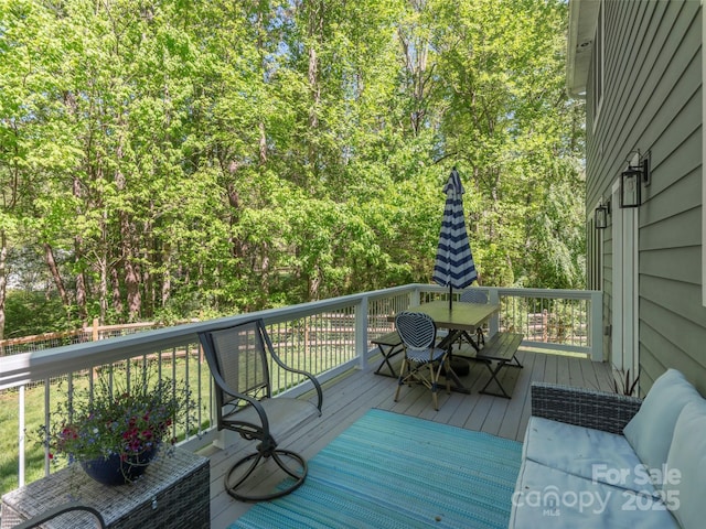 deck featuring a view of trees and outdoor dining area