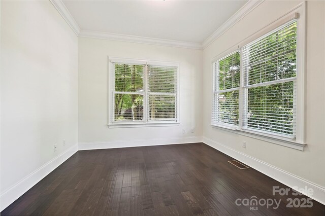 empty room with baseboards, ornamental molding, visible vents, and dark wood-type flooring