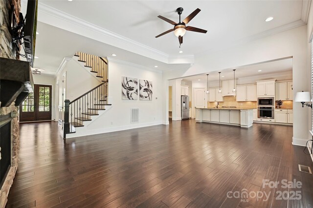 unfurnished living room featuring stairway, ceiling fan, dark wood finished floors, and visible vents