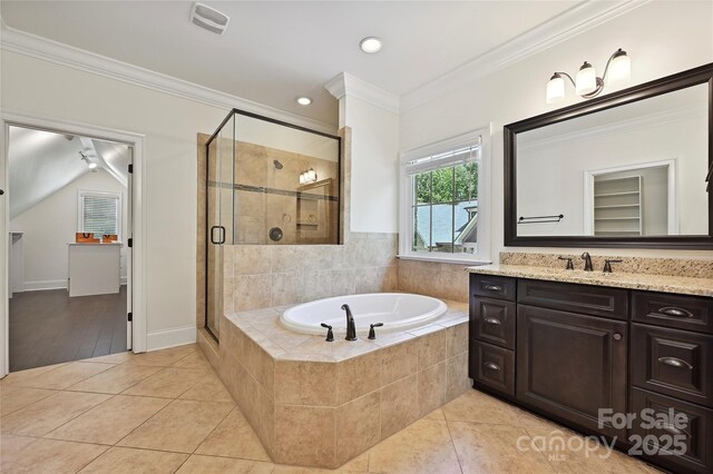 full bath featuring tile patterned flooring, vanity, ornamental molding, a garden tub, and a stall shower