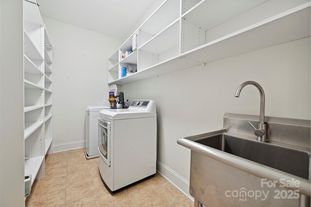 laundry room featuring washing machine and clothes dryer, laundry area, a sink, and baseboards