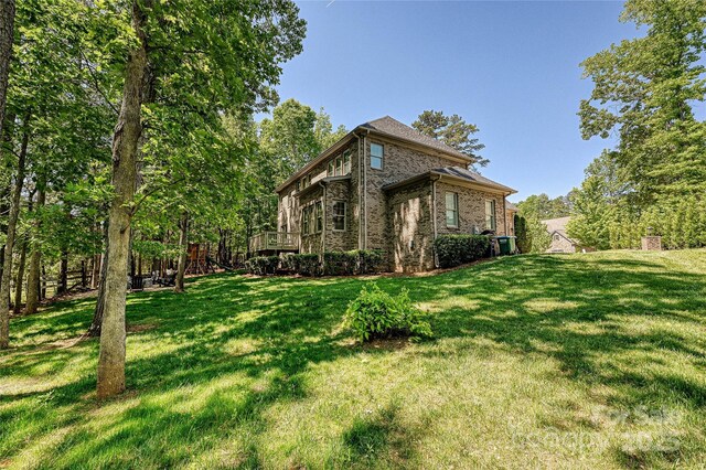 view of home's exterior featuring a lawn, a wooden deck, and brick siding