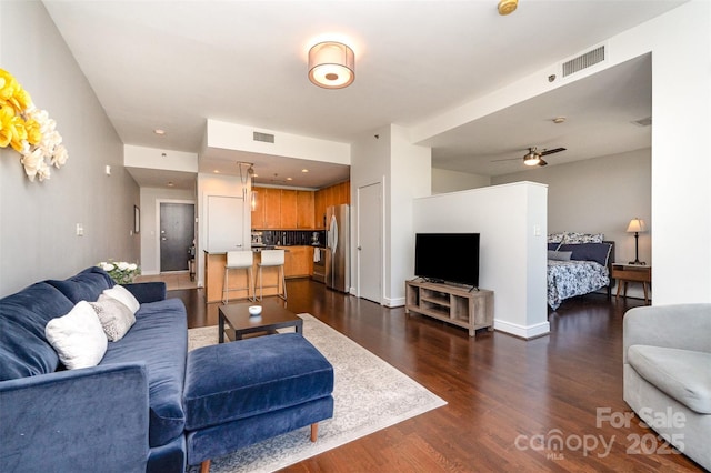 living room with a ceiling fan, dark wood-style flooring, and visible vents