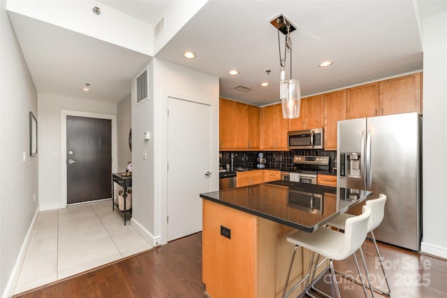 kitchen with visible vents, baseboards, a center island, tasteful backsplash, and stainless steel appliances