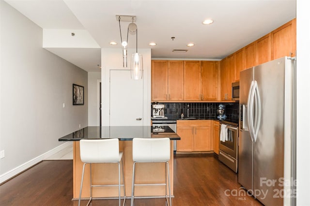 kitchen featuring dark wood-style flooring, dark countertops, recessed lighting, tasteful backsplash, and stainless steel appliances